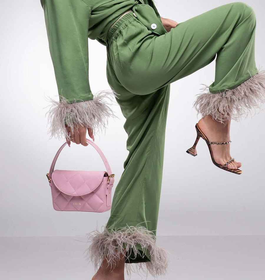 Woman styling pink Kate Baguette Mini Bag with green feather-trimmed outfit and brown heels - even-online
