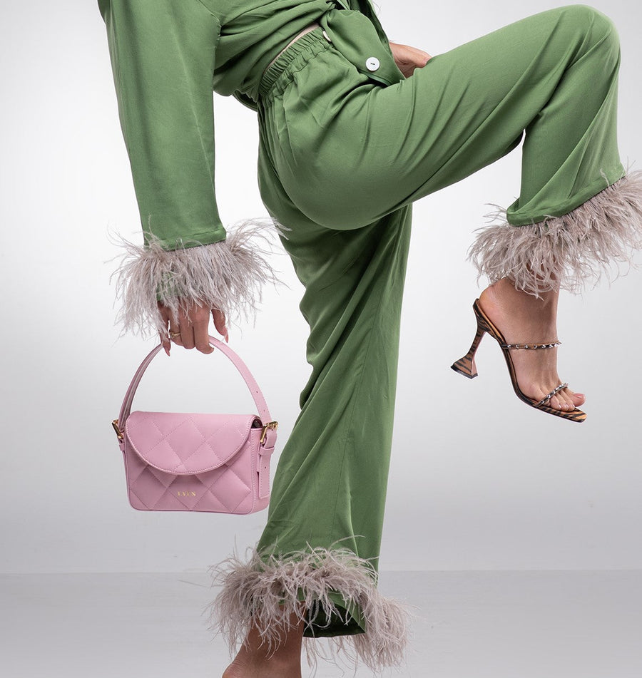 Woman styling pink Kate Baguette Mini Bag with green feather-trimmed outfit and brown heels - even-online