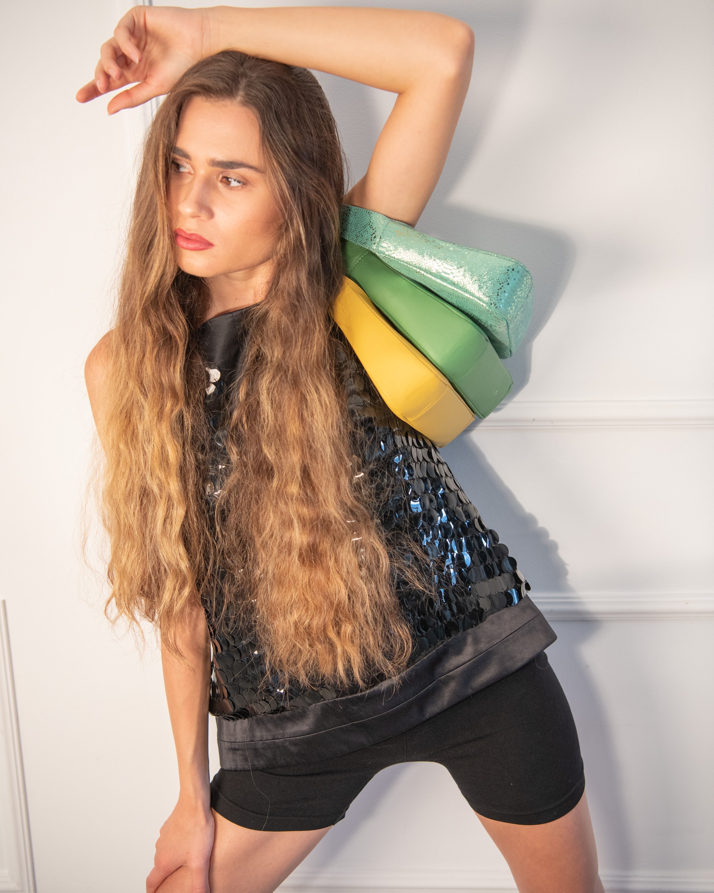 Group of models in stylish outfits striking dynamic poses in a dramatic fashion shoot against a bright background.
