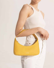 Woman carrying Zoe mini baguette bag in yellow leather by even-online