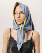 Woman wearing a blue and olive color scarf on a plain background