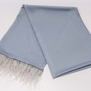 A blue scarf with ostrich feather fringe laid out on a plain surface.