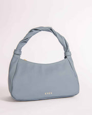 A light blue Monna mini tote bag with a triangular shape and a twisted handle, set against a plain background.