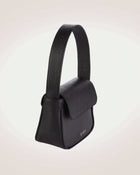 Side view of luisa mini black leather flap handbag with gold tone logo of even brand.