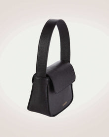 Side view of luisa mini black leather flap handbag with gold tone logo of even brand.