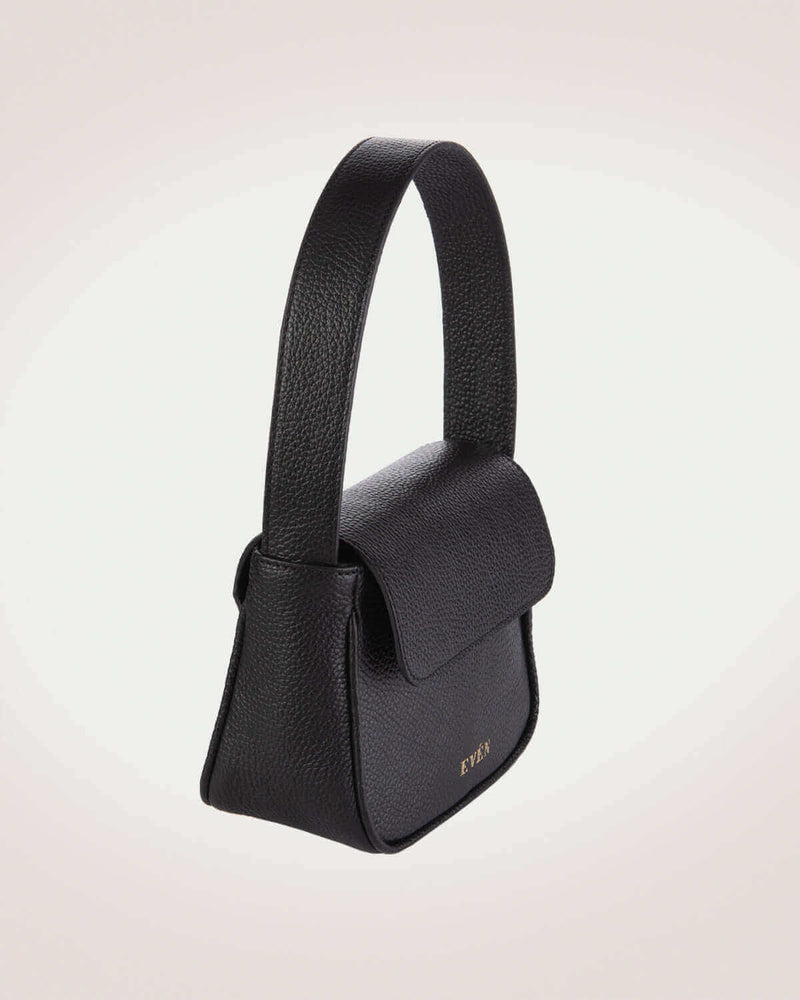 Side view of luisa mini black leather flap handbag with gold tone logo of even brand.