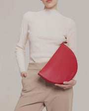 Model is showcasing leyza clutch in red calfskin leather.