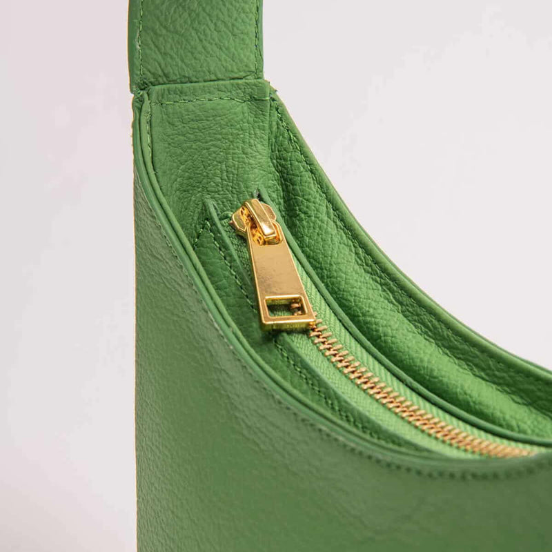 Zoe green handbag with a gold zipper on a light gray background
