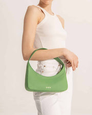 Woman holding Zoe mini baguette bag in green leather 