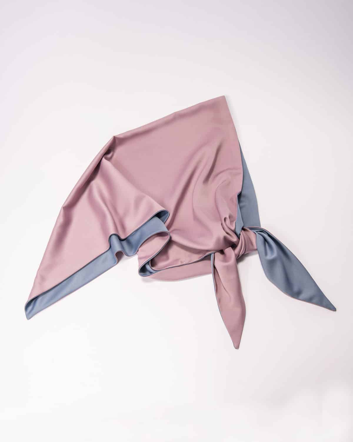 A double-sided satin head scarf with pink and blue sky colors tied in a knot, laying flat on a white background.