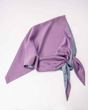 A double-sided satin head scarf with purple and blue sky colors tied in a knot.