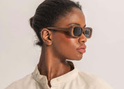Wooden frame sunglasses with dark lenses styled on model in profile view